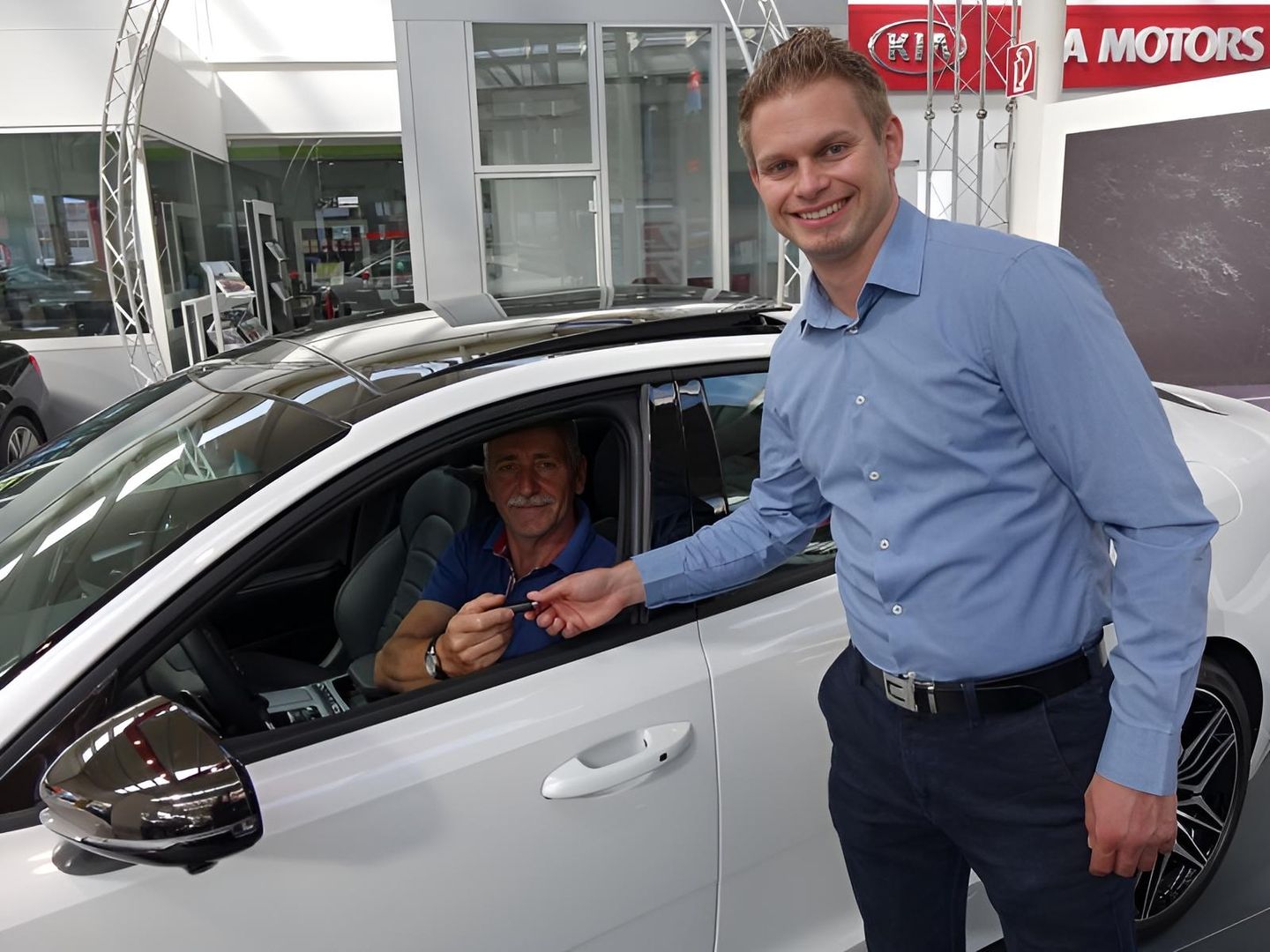 Ein Verkäufer übergibt einem Kunden den Schlüssel